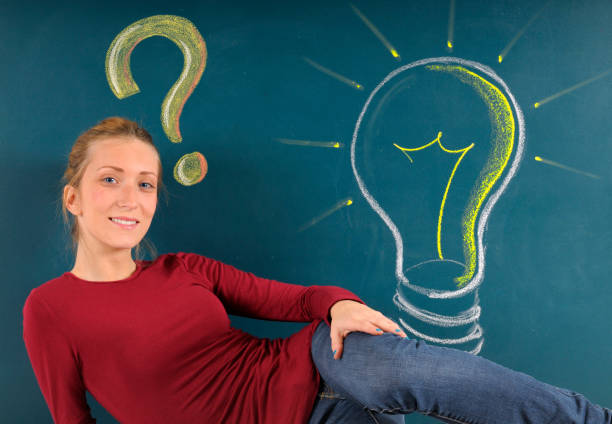 Young woman with question mark and light bulb on blackboard