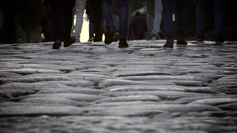 feet and legs of people walking on ancient way of the center of Rome