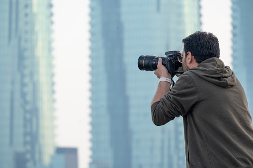 Manama, Bahrain - December 28, 2023: Male Photographer taking photos of skyline Manama City Bahrain