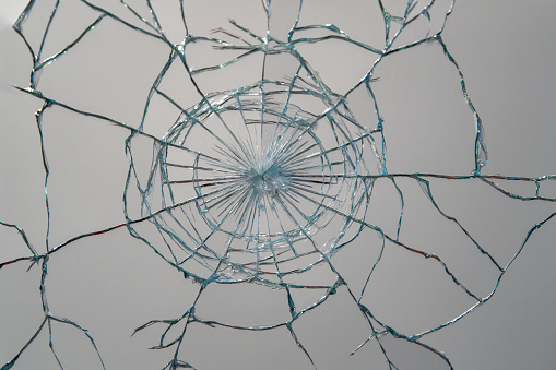 Bullet hole in broken glass on a white background. Shards of glass. High quality photo