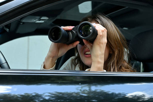 istock A young woman funny spying on someone through binoculars from a car 2028040793