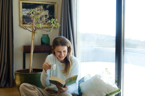 istock Woman reading a book while relaxing at home 2028059006