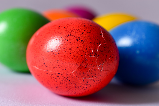 Holidays: hand painted multi colored Easter eggs shot white striped table leaving useful copy space for text and/or logo. Some candies, sugar sprinkles and a red ribbon complete the composition. High resolution 42Mp studio digital capture taken with Sony A7rII and Sony FE 90mm f2.8 macro G OSS lens