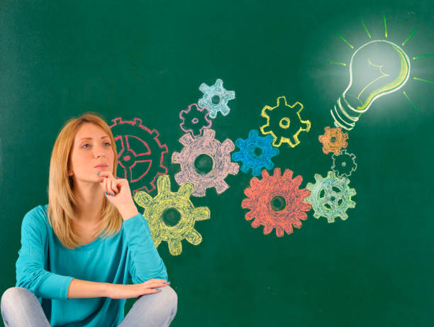 Young woman with gear wheel and light bulb on blackboard