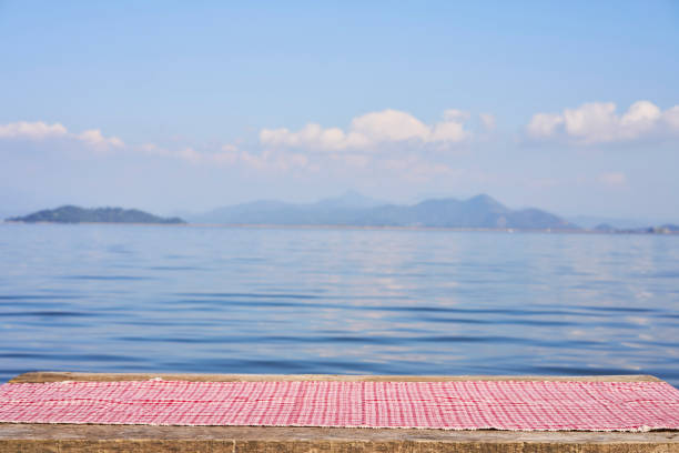 Empty wooden table with tablecloth over summertime lakeside background