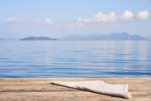 Empty wooden table with tablecloth over summertime lakeside background