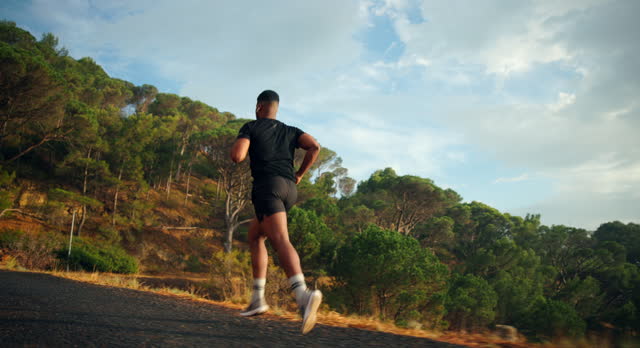 Young man are exercising with outdoor running with a mountain background. When the sun sets in Thailand in summer, Concept healthy running and outdoor exercise,Tracking dolly shot.