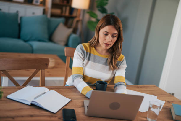 istock mature woman works on her laptop from home and does paperwork. 2028131828