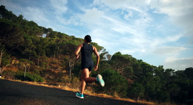 Young woman are exercising with outdoor running with a mountain background. When the sun sets in Thailand in summer, Concept healthy running and outdoor exercise,Tracking dolly shot.