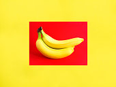 Yellow banana on the yellow and red background. Copy space. Close-up.