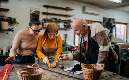 Small group of people making leather products on a work bench