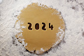 2024 numbers cut from rolled raw cookie dough on flour table