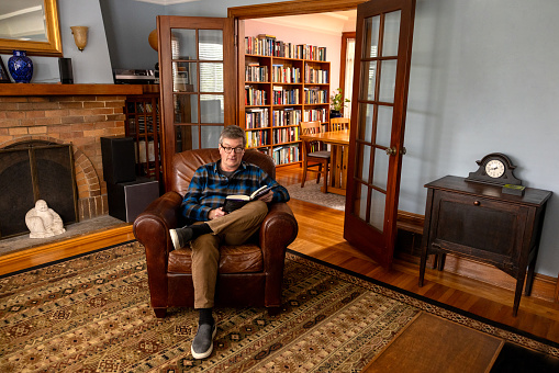 Inside the home of a mature man using and enjoying his home library in an authentic Victorian home.