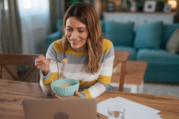 istock A smiling woman talks on a video call and eats breakfast. 2028205431