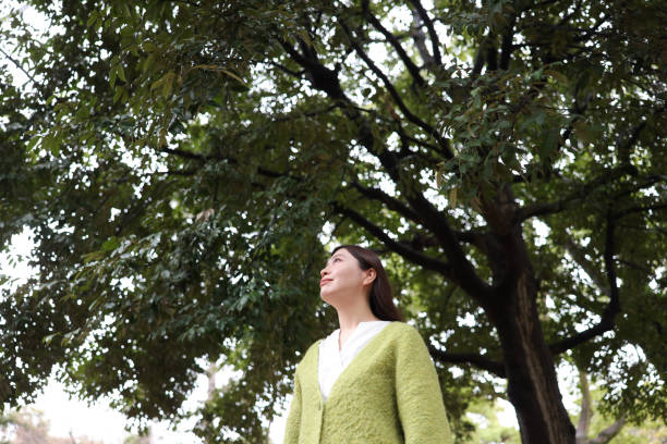 An Iranian environmentalist hugging a tree that wasn't cut down in a public park clearing operation. She is wearing long brown hair, earrings, makeup, necklace, red nail polish and a green dress.