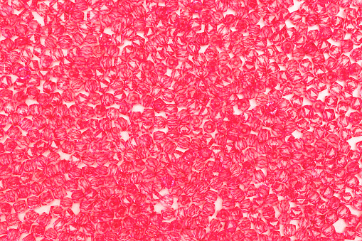 Texture made from acrylic square beads on a pink background.