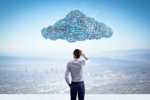 istock Back view of businessman standing under abstract digital cloud with programming language on bright sky background. Digital storage, database, network and technology concept. 2028227983