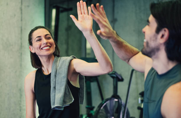 Couple giving each other high five after a successful workout in a gym.