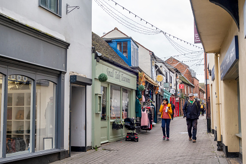 A few people passing small independent shops in Eld Lane, Colchester, Essex, Eastern England, on an overcast autumn day.