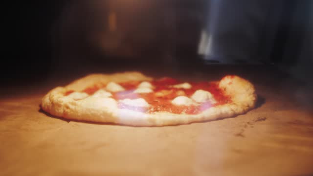 Traditional italian street food cooking, preparation of a Margherita Neapolitan style pizza with buffalo mozzarella, tomato sauce and basil in oven. High kitchen cuisine restaurant.
