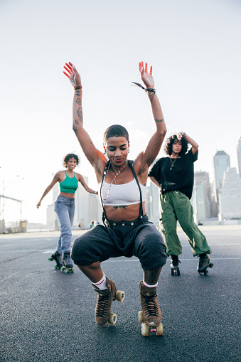 Women with quad skates and wearing urban clothes dancing and exercising with roller skates in Brooklyn New York.