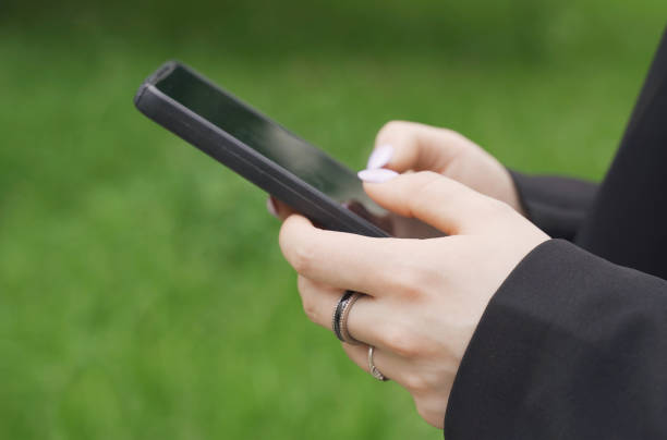 A woman is typing a message on her smartphone. Close-up of hands.