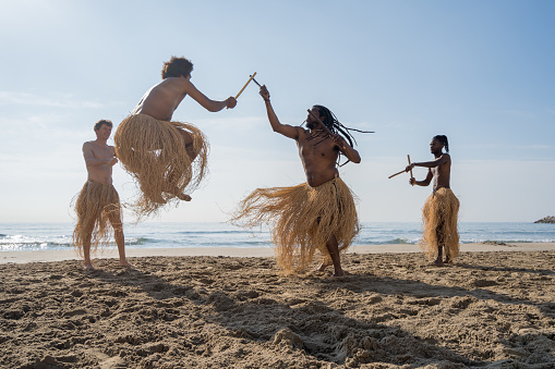 Men practicing capoeira (Brazilian martial art that combines elements of dance, acrobatics and music) on the beach