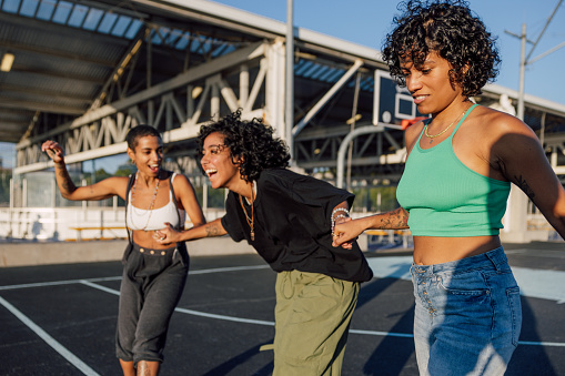 Women with quad skates and wearing urban clothes dancing and exercising with roller skates in Brooklyn New York.