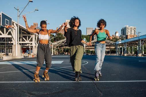 Women with quad skates and wearing urban clothes dancing and exercising with roller skates in Brooklyn New York.