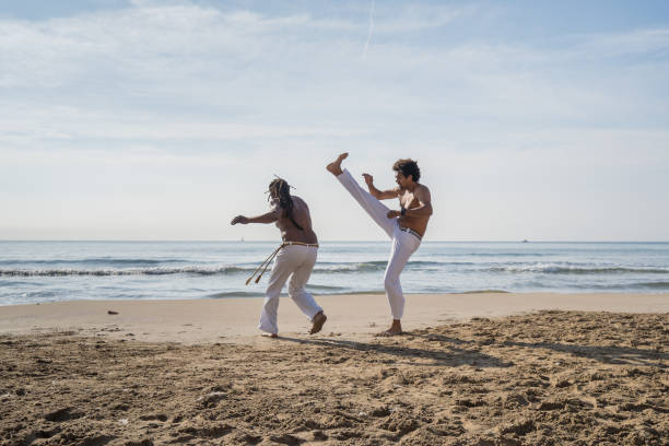 Athletic capoeira Brazilian dancers having a fight in the beach