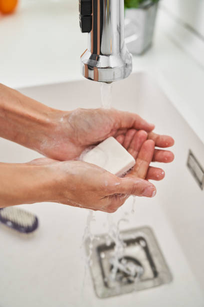 Person washing hands with soap under water in sink