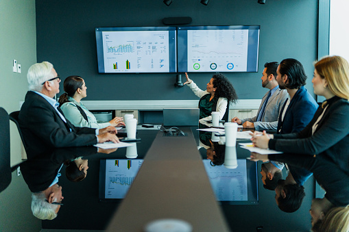 Mid adult businesswoman talking with coworkers on business meeting