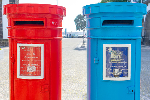two cylindrical-shaped mailboxes, one red and the other blue.  Ponta Delgada-São Miguel-Açores-Portugal.