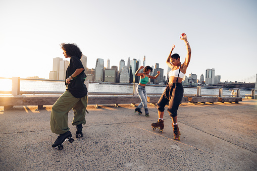 Women with quad skates and wearing urban clothes dancing and exercising with roller skates in Brooklyn New York.