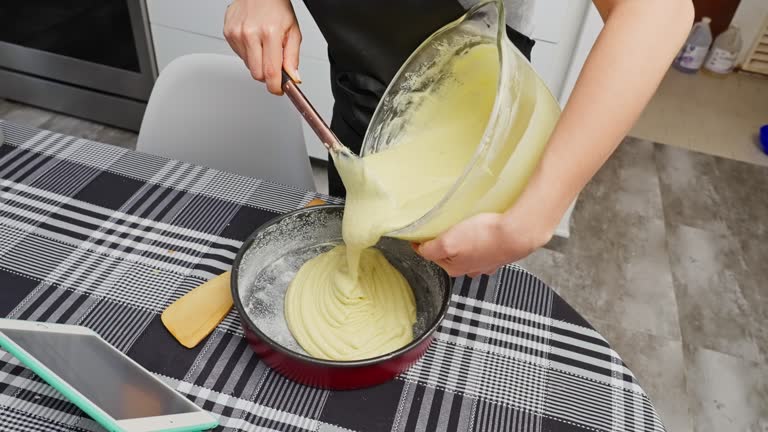 Hispanic young woman pouring cake batter into a baking pan
