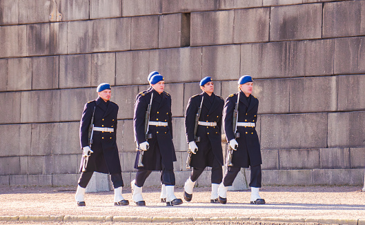Stockholm, Sweden - February 18th 2024: Swedish Royal Guards in navy blue winter uniform walking infront of the Royal Palace in Stockholm.