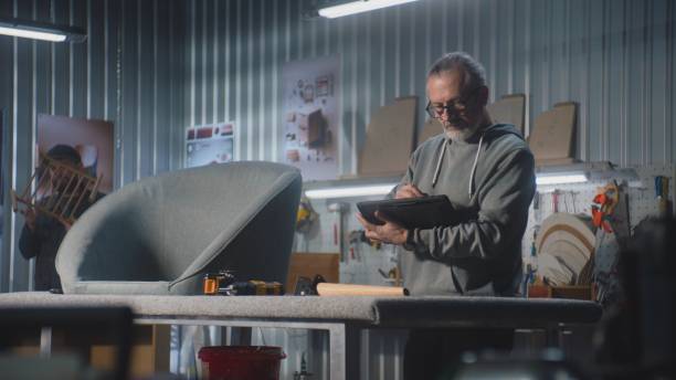 istock Mature carpenter or designer uses digital tablet in furniture workshop 2028344879