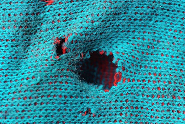 green fabric texture from a torn woolen sweater with a hole