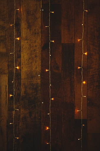 Christmas tree adorned with gold and white lights on wooden floor