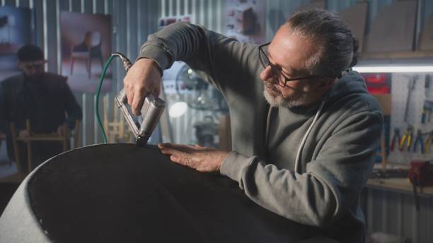 istock Mature carpenter makes upholstery of chair using staple gun 2028354260