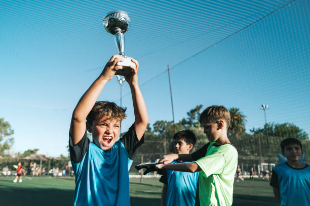 istock boy lifting up soccer winner cup 2028366439