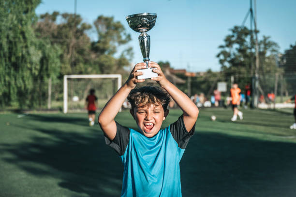 istock boy lifting up soccer winner cup 2028371712