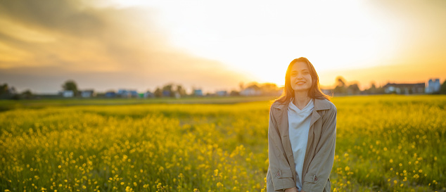 happy young woman in summer at sunset in a yellow field enjoys life in addiction rehabilitation.