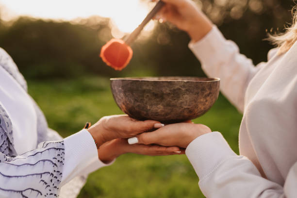 Close up of the hands of an unrecognizable mother  and daughter enjoying a sound bowl therapy technique together in their garden stock photo
