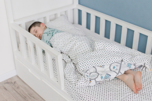 Sleeping caucasian boy in blue pyjama in his bed