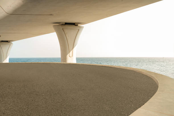 empty asphalt road and bridge over sea during daytime. copy space for parking lot.