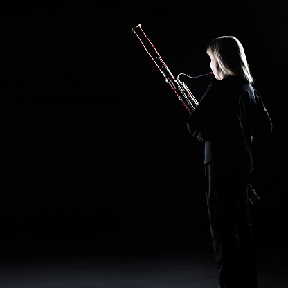 Bassoon woodwind instrument player. Classical musician woman playing orchestral bass. Wind instruments
