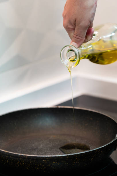 istock Chef pouring oil from a bottle into a frying pan in the kitchen 2028426577