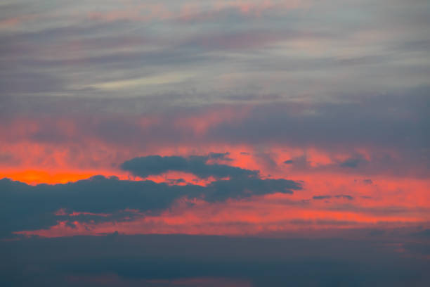 Vibrant colors background photo of the awe-inspiring beauty of the sky as the sun sets after a tropical storm, painting it in a vibrant array of colors. From shades of blue and orange forming a border at sunrise to a colorful burning sky with hues of red, blue, purple, yellow, pink, and orange at sunset, the sky becomes an exquisite canvas of nature's artistry. This amazing cloudscape, with its interplay of light and shadow, captures the essence of tranquility and wonder as the day transitions into twilight.\