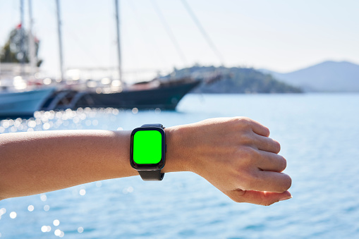 Hand wearing smart watch on blurred Sea background. wearable gadget concept